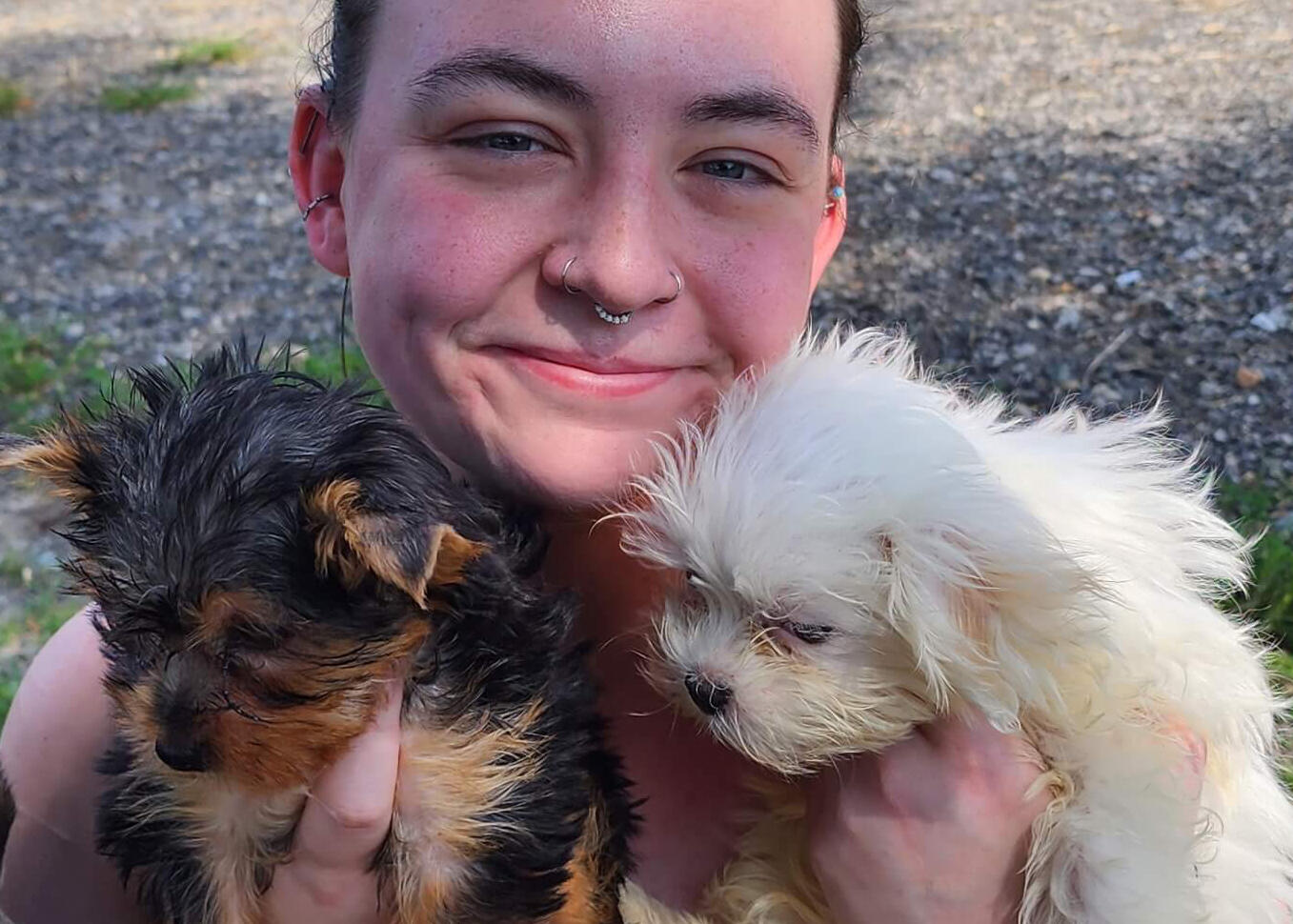 A woman is holding two small puppies that she is looking after.